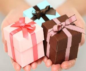 Gift boxes in light pink, brown and light green colours wrapped with satin ribbons around them.